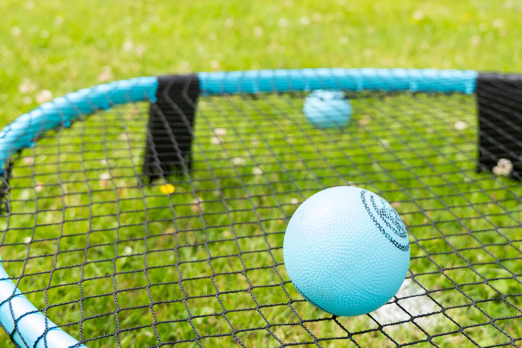 A spikeball style ball sat on a roundnet set in a grassy field on a sunny day - what is roundnet